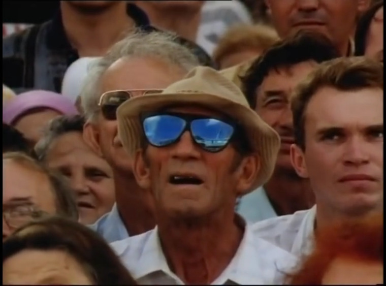 still aus pawel pawilowskis film Tripping with Zhirinovsky. mann steht in der menge. in seiner 
		    sonnenbrille reflektiert sich der himmel